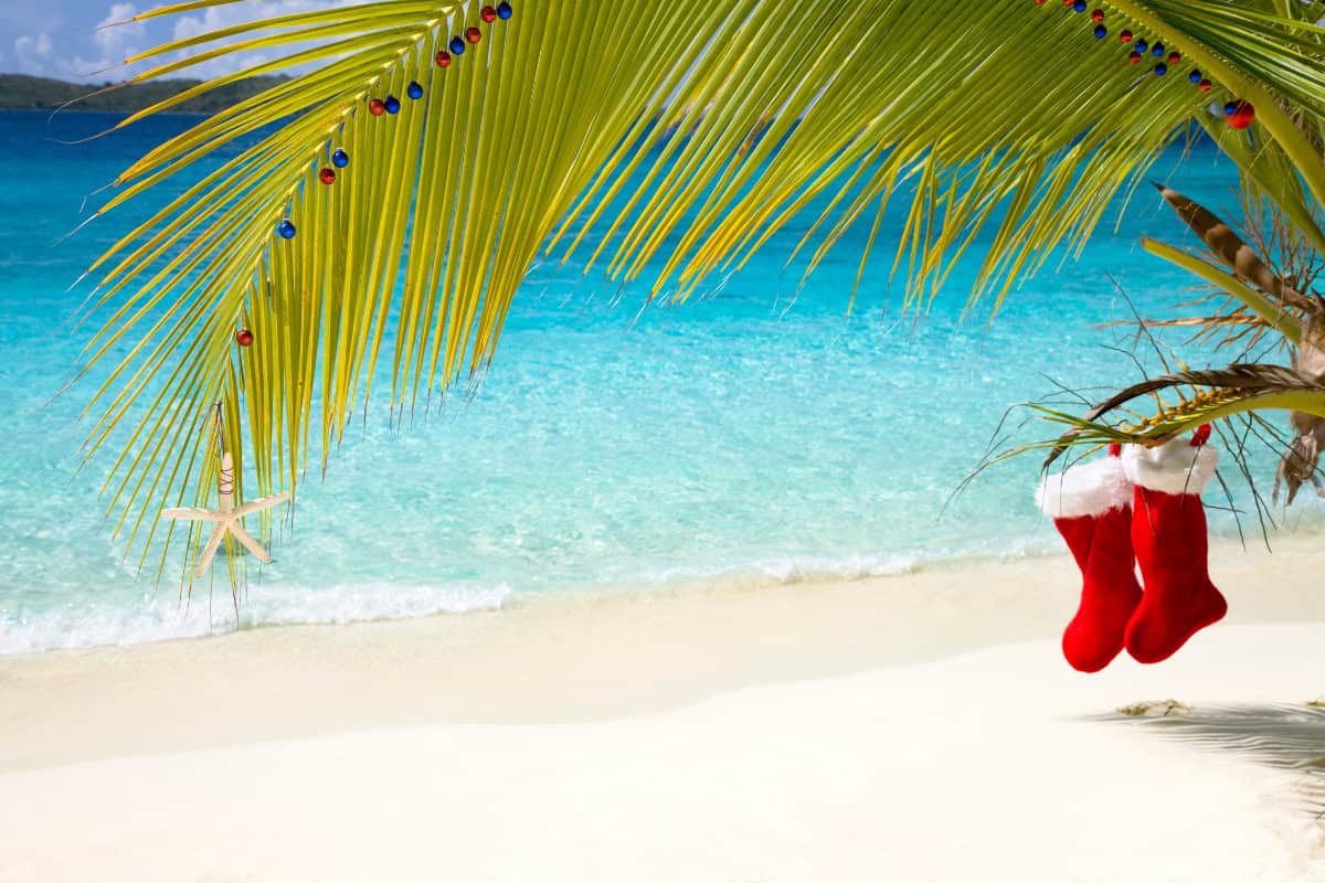 Plage tropicale avec palmiers décorés de boules de Noël et chaussettes rouges suspendues, symbole d’un Noël ensoleillé dans les îles, idée de destination paradisiaque pour fêter Noël sous le soleil