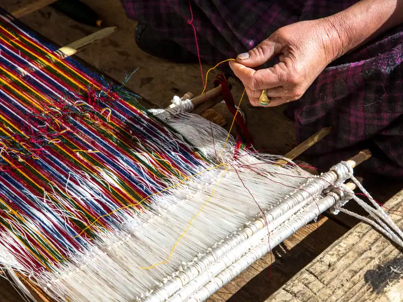 Femme faisant du tissage artisanal au Bhoutan Activité immersive séjour traditionnel