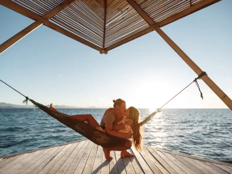 Couple s'embrassant sur une île aux Maldives face à la mer et sur un hamac Itinéraire romantique en duo