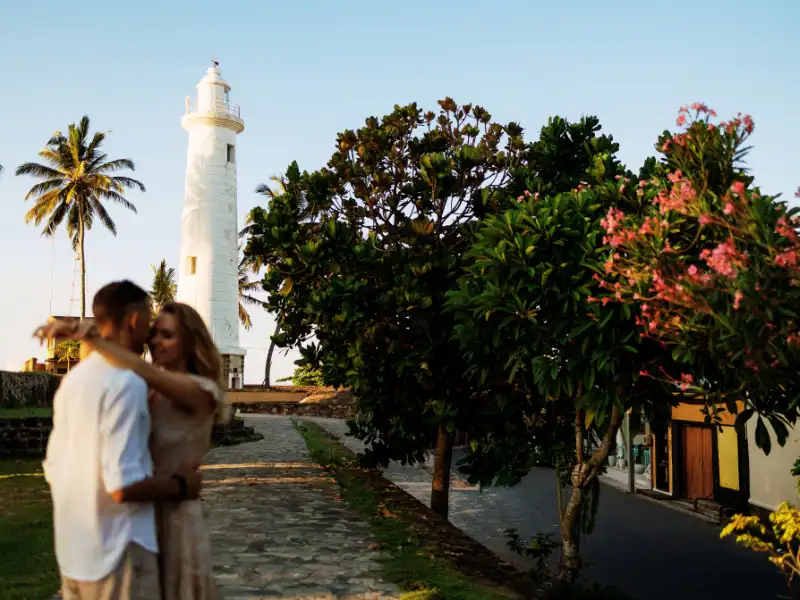 Couple s'enlaçant lors d'un voyage romantique à Galle Fort au Sri Lanka devant le phare au coucher du soleil