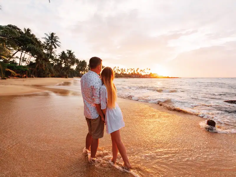 Couple se tenant côte à côté et observant le couché de soleil sur une plage paradisiaque au Sri Lanka
