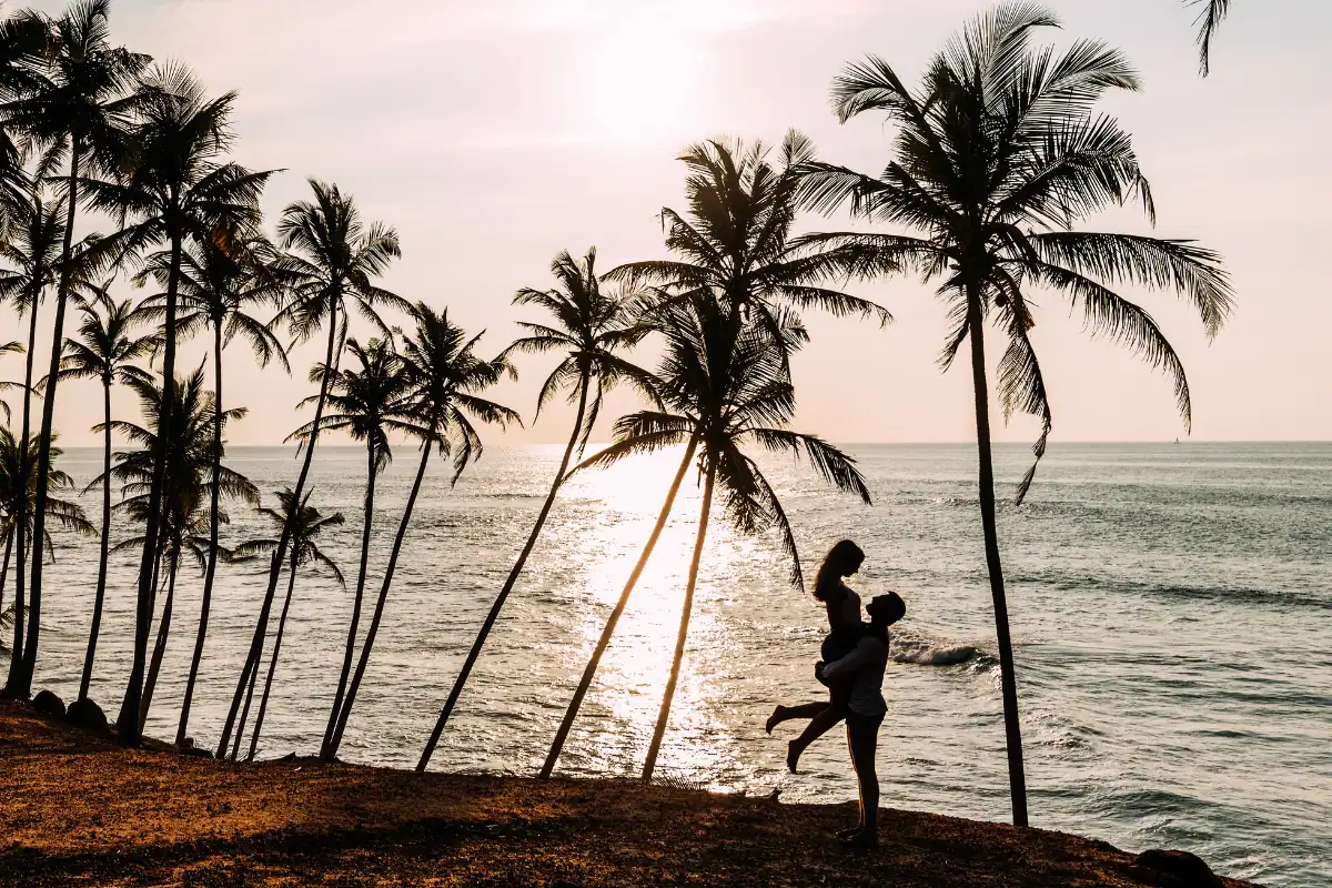 Couple amoureux en lune de miel au Sri Lanka au coucher du soleil sur une plage bordée de palmiers face à l’océan Indien
