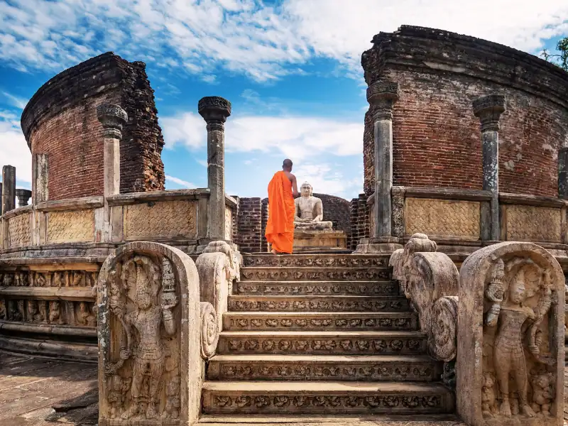 Vue sur une temple situé sur le site classé de Polonnaruva dans le Triangle culturel au Sri lanka avec un moine face à une statue de Bouddha