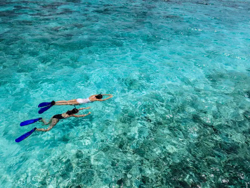 Personnes faisant du snorkeling dans les eaux turquoises des Maldives
