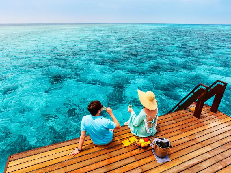 Couple se prélassant au bord d'une eau turquoise et translucide aux Maldives pendant leur voyage de vacances d'été